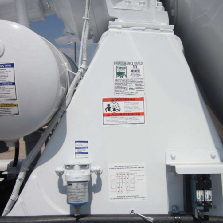 Close-up of electrical components and warning labels on a concrete mixer truck, highlighting wiring, switches, and performance information